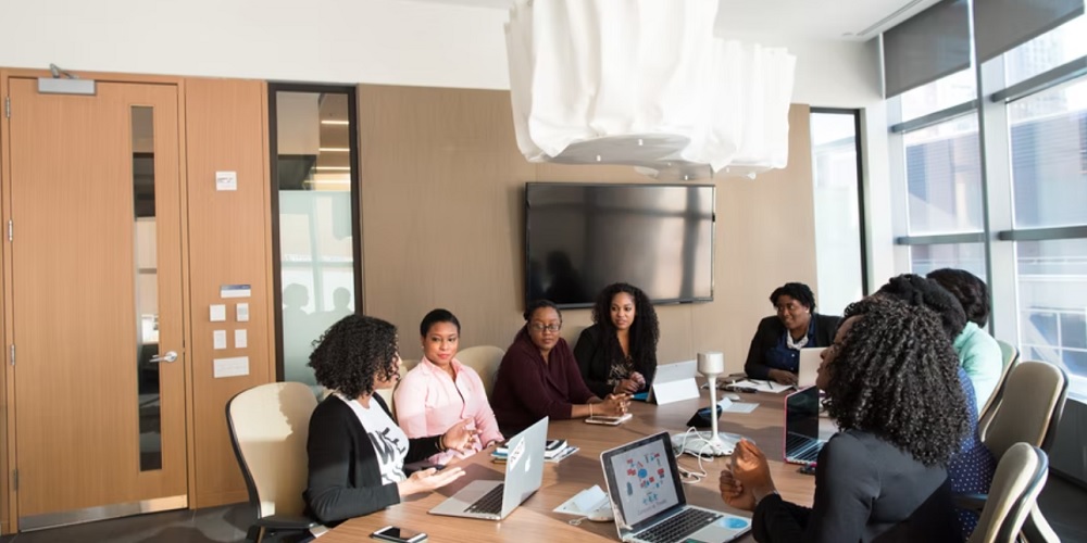 Picture of women of colour in technology having a discussion in a boardroom. 