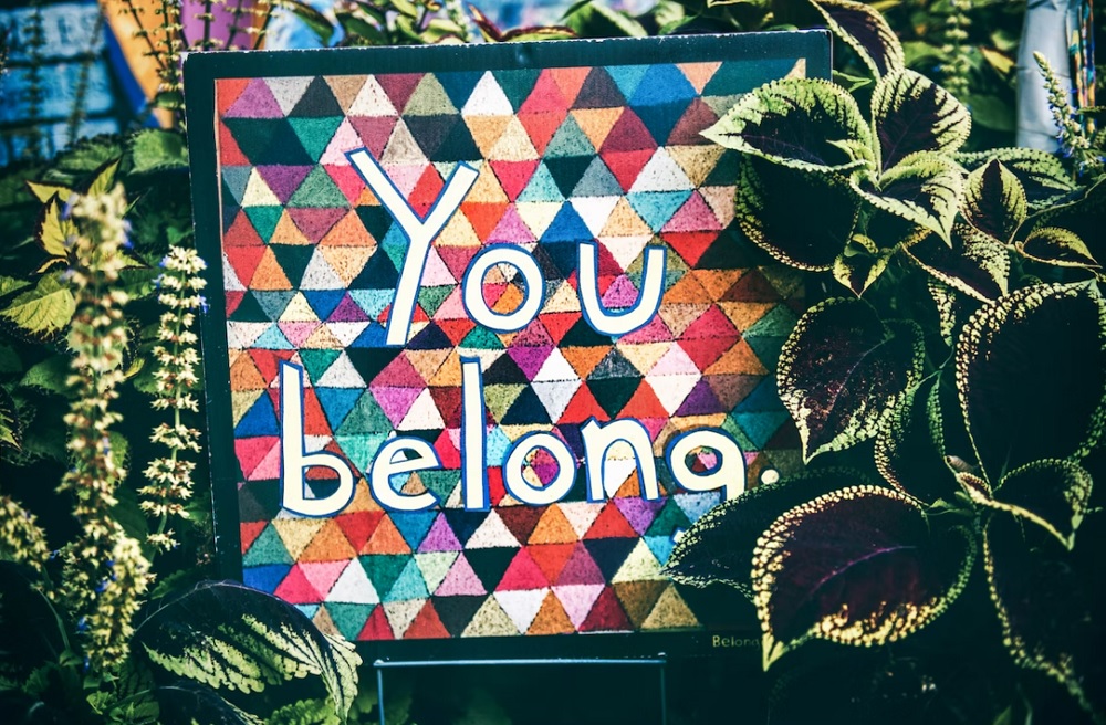 The text You Belong on a colourful background surrounded by plants.